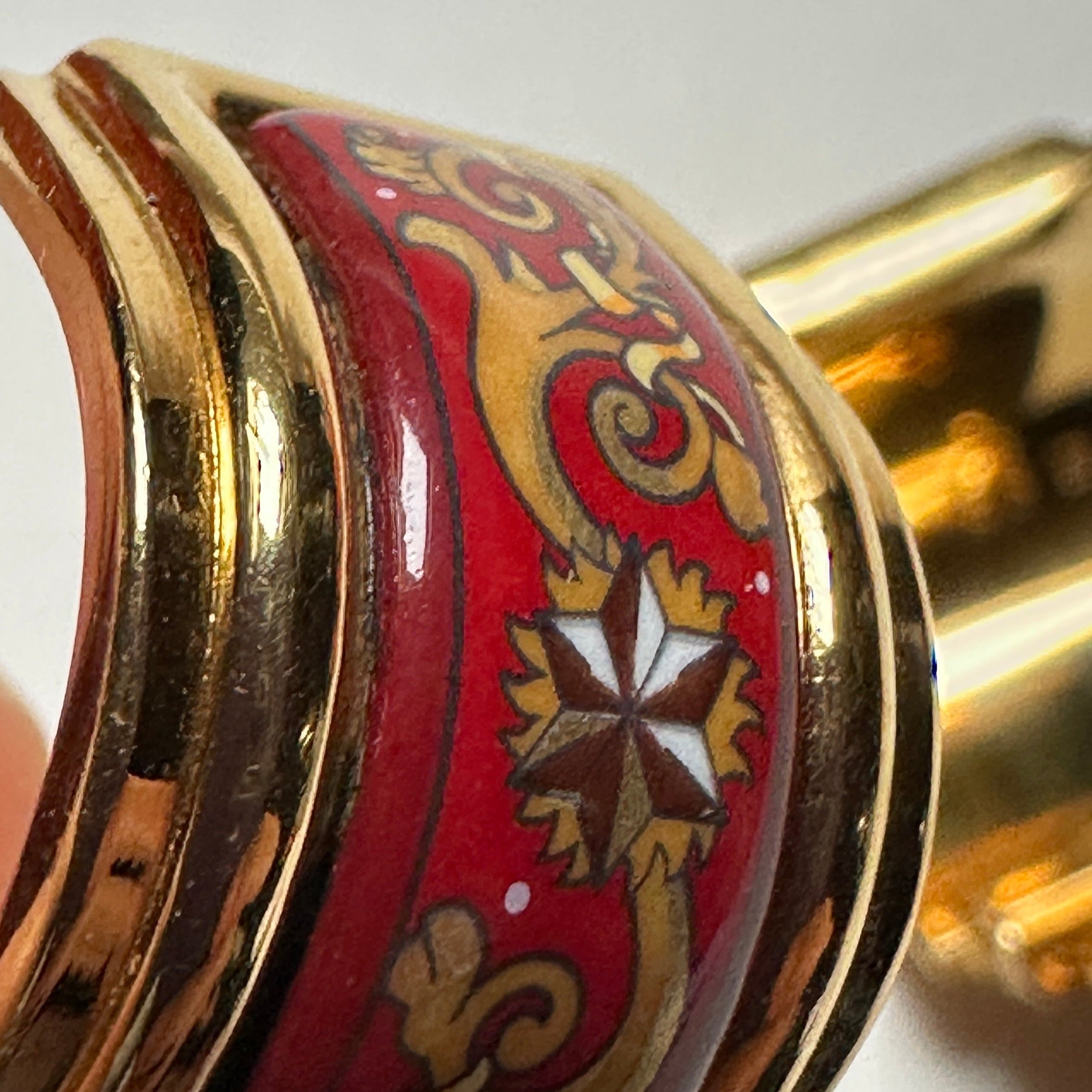 vue de trois quart profil en gros plan d'une boucle d'oreille Hermès légère patine sur la dorure