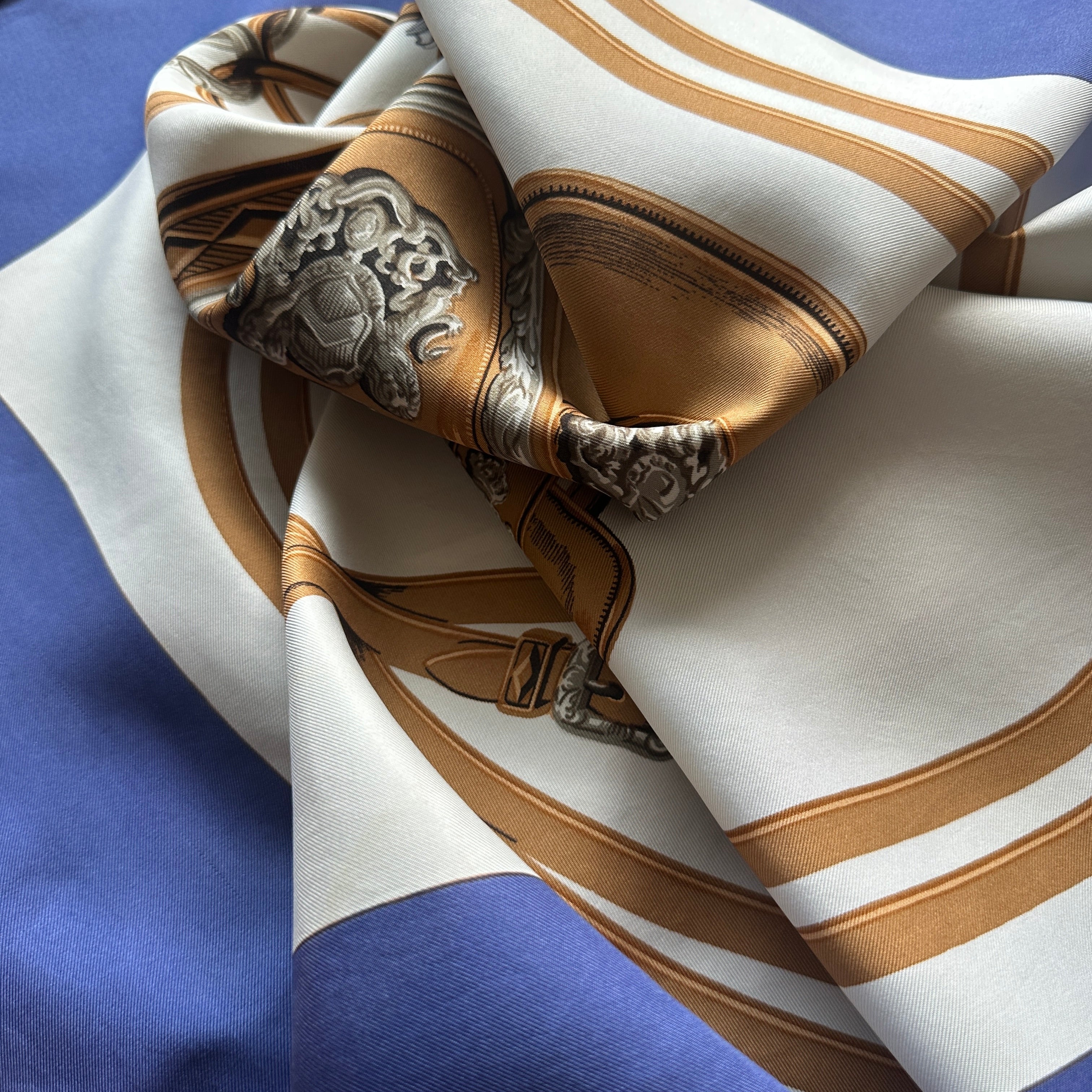 foulard carré Hermès enroulé sur lui même pour visualiser le rendu de la palette de couleur creme marron et bleu lavande