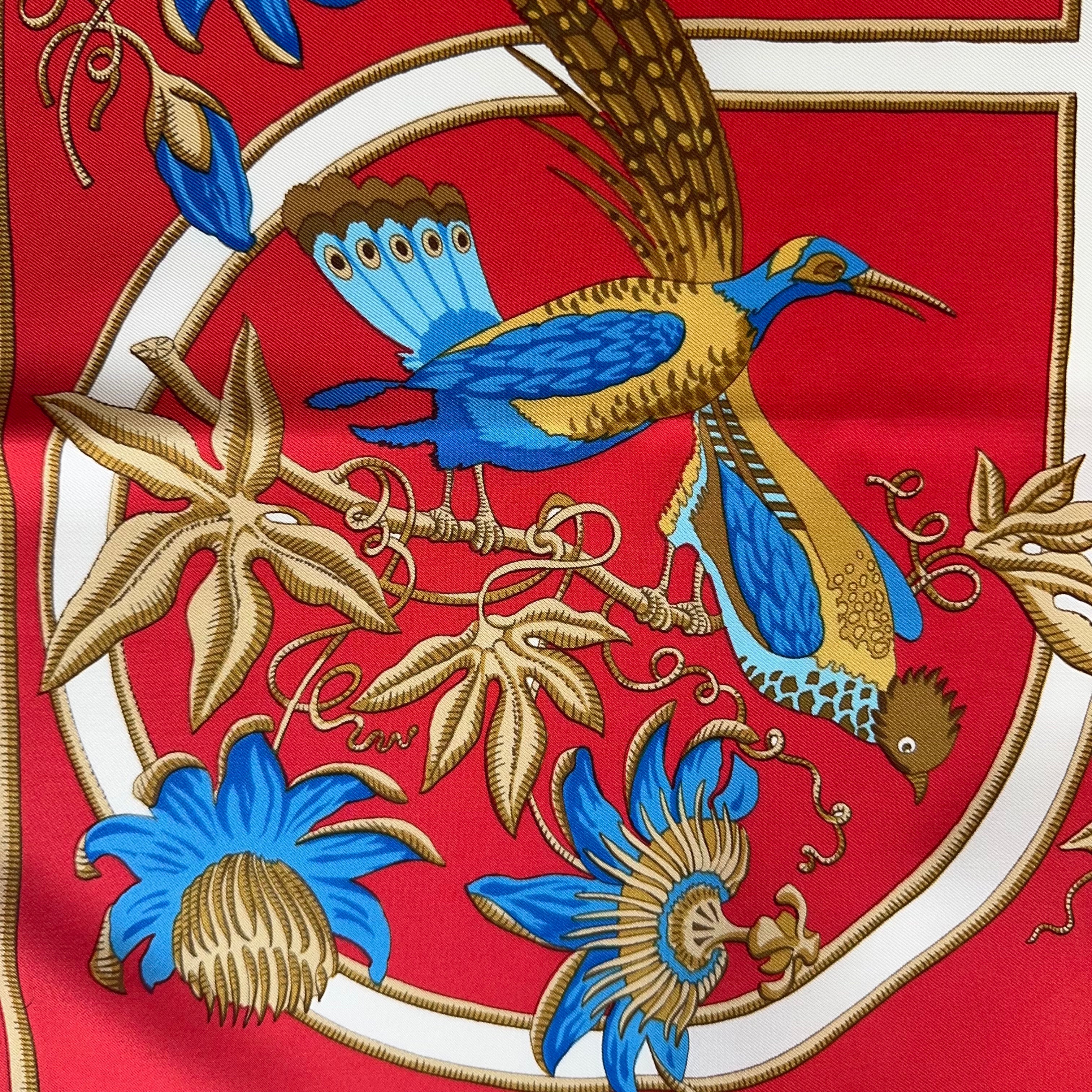 Détail artistique des motifs floraux : fleurs de la passion bleues et feuillages dorés entourant un petit oiseau coloré.