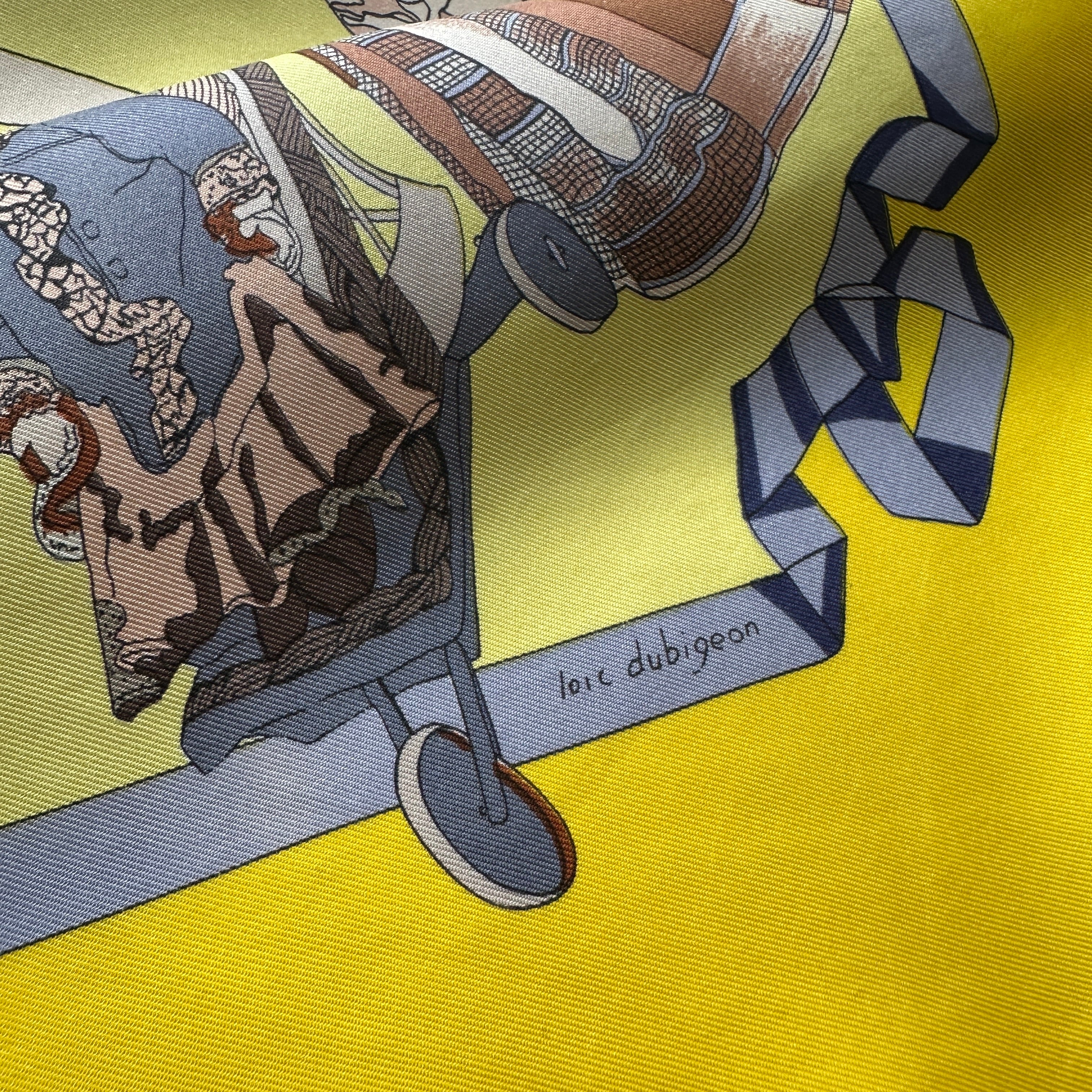 Signature manuscrite de l'artiste "Loïc Dubigeon" discrètement intégrée dans le coin du foulard.