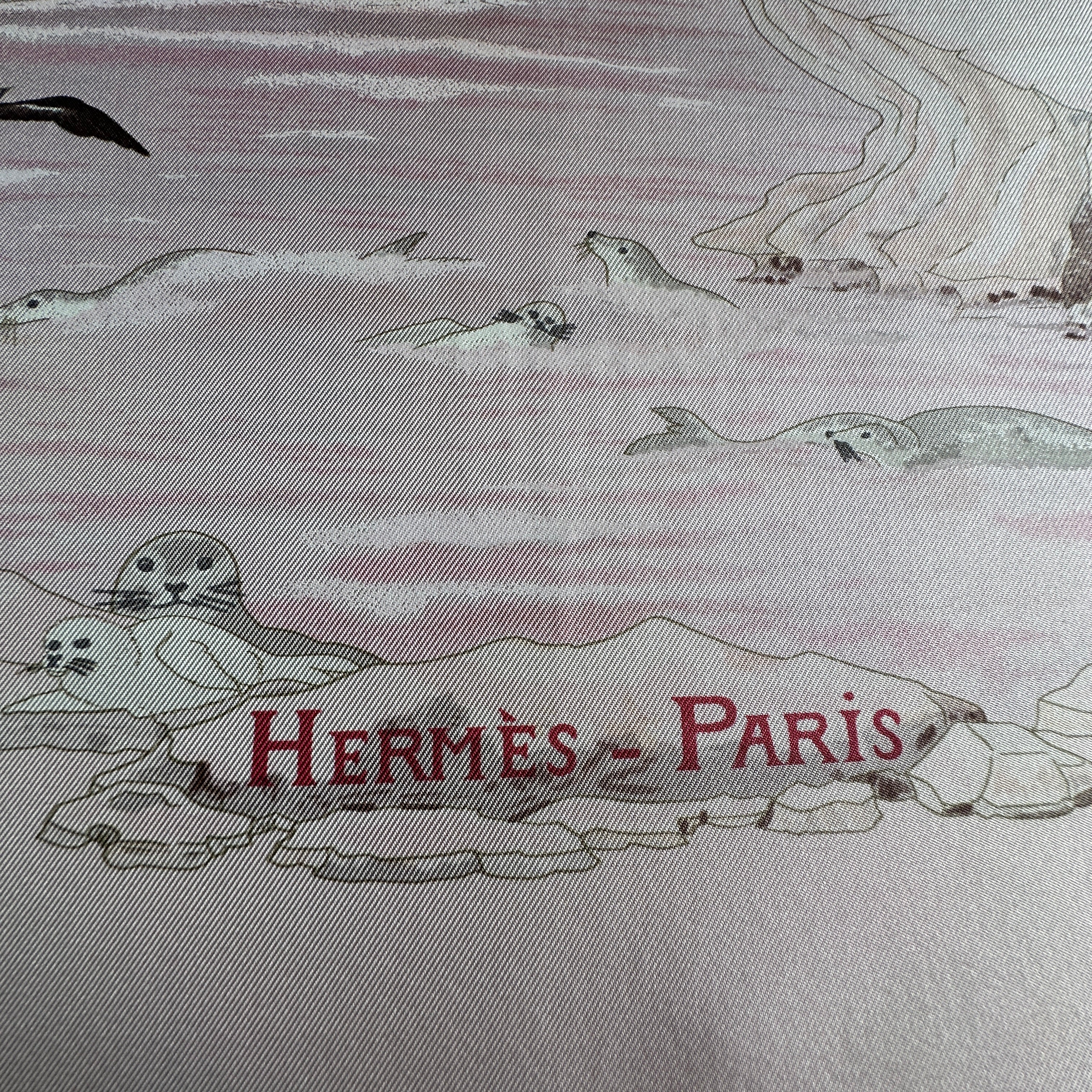 Signature "Hermès - Paris" centrée en bas du foulard entourée de motifs marins et phoques.