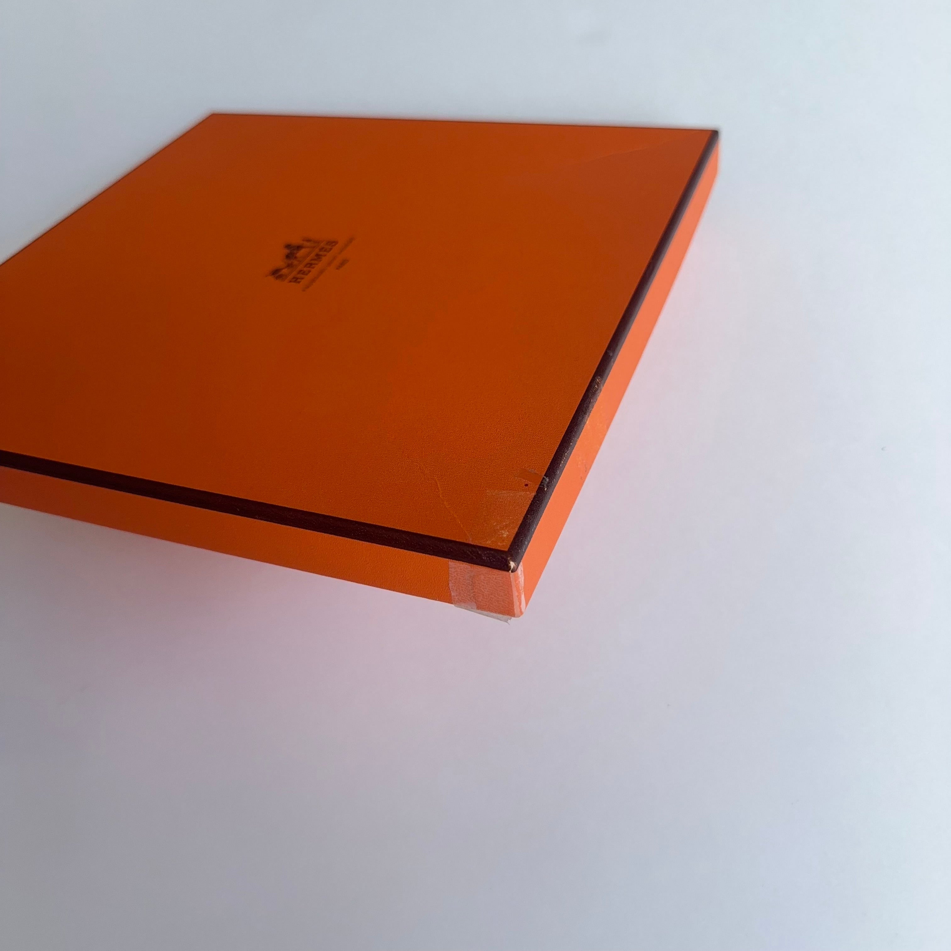 Photo de détail montrant l'état de la boîte orange (léger défaut/scotch sur un angle) pour une transparence totale sur le packaging.