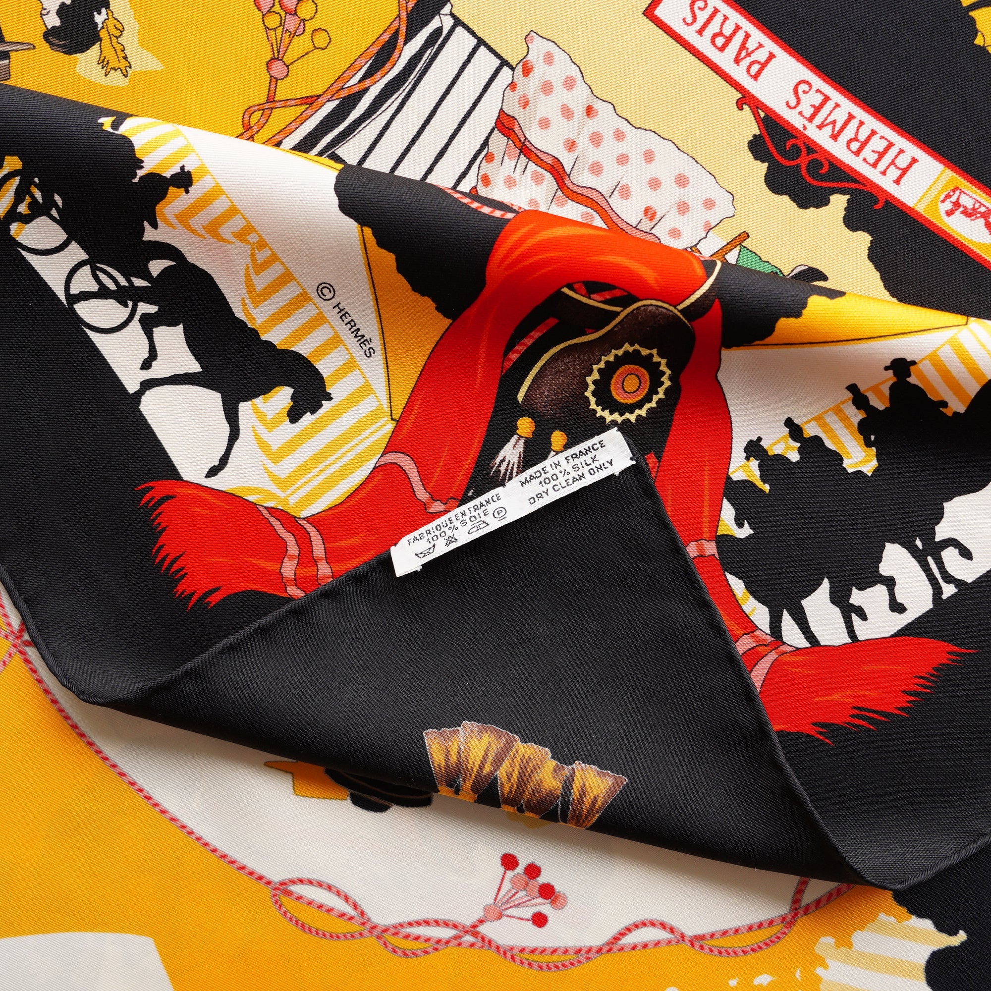 Zoom sur l'étiquette de composition et le roulotté main impeccable du foulard Hermès Feria de Sevilla.