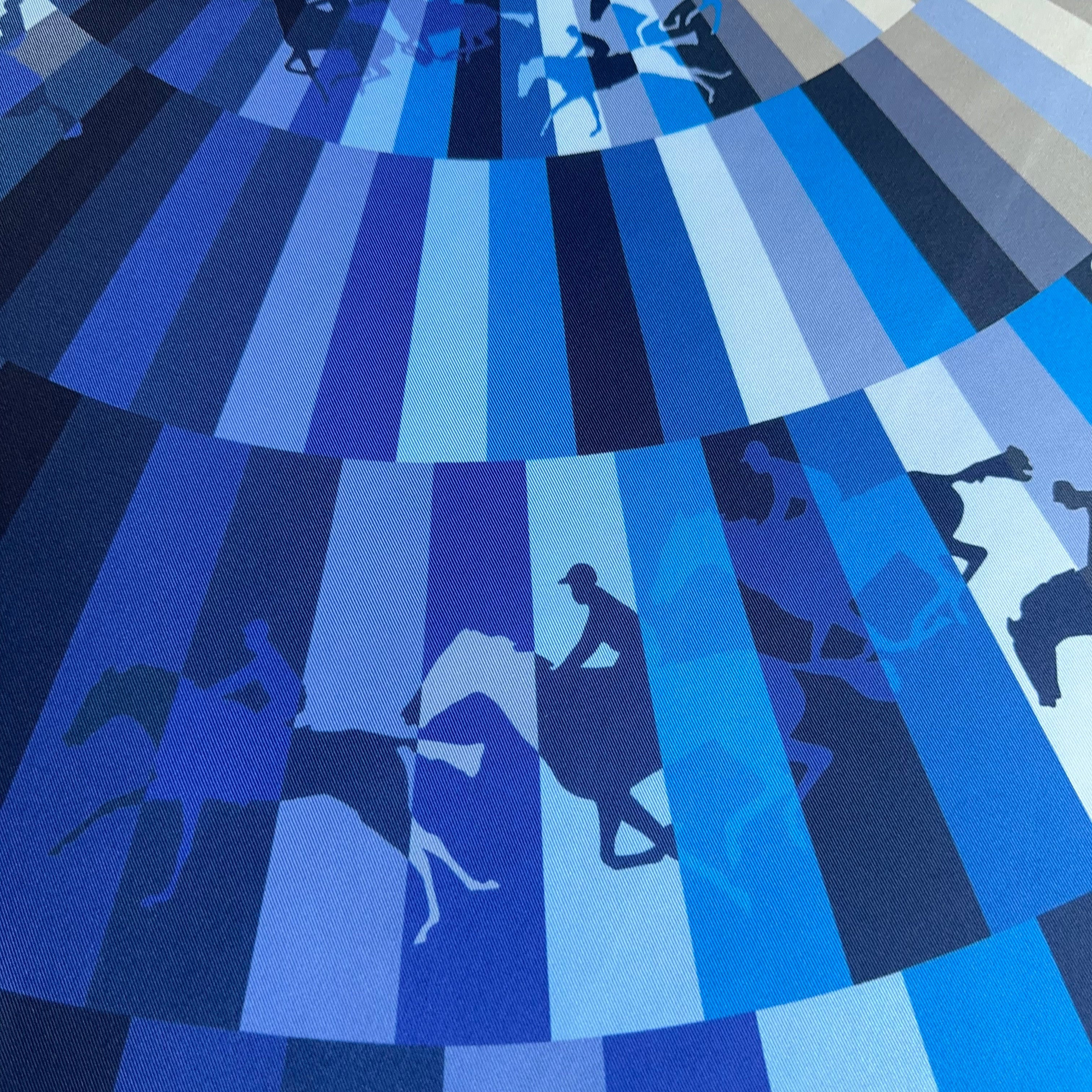 Gros plan sur la partie basse du carré : alternance de bandes bleu marine, ciel et blanc créant le mouvement des jockeys et chevaux.